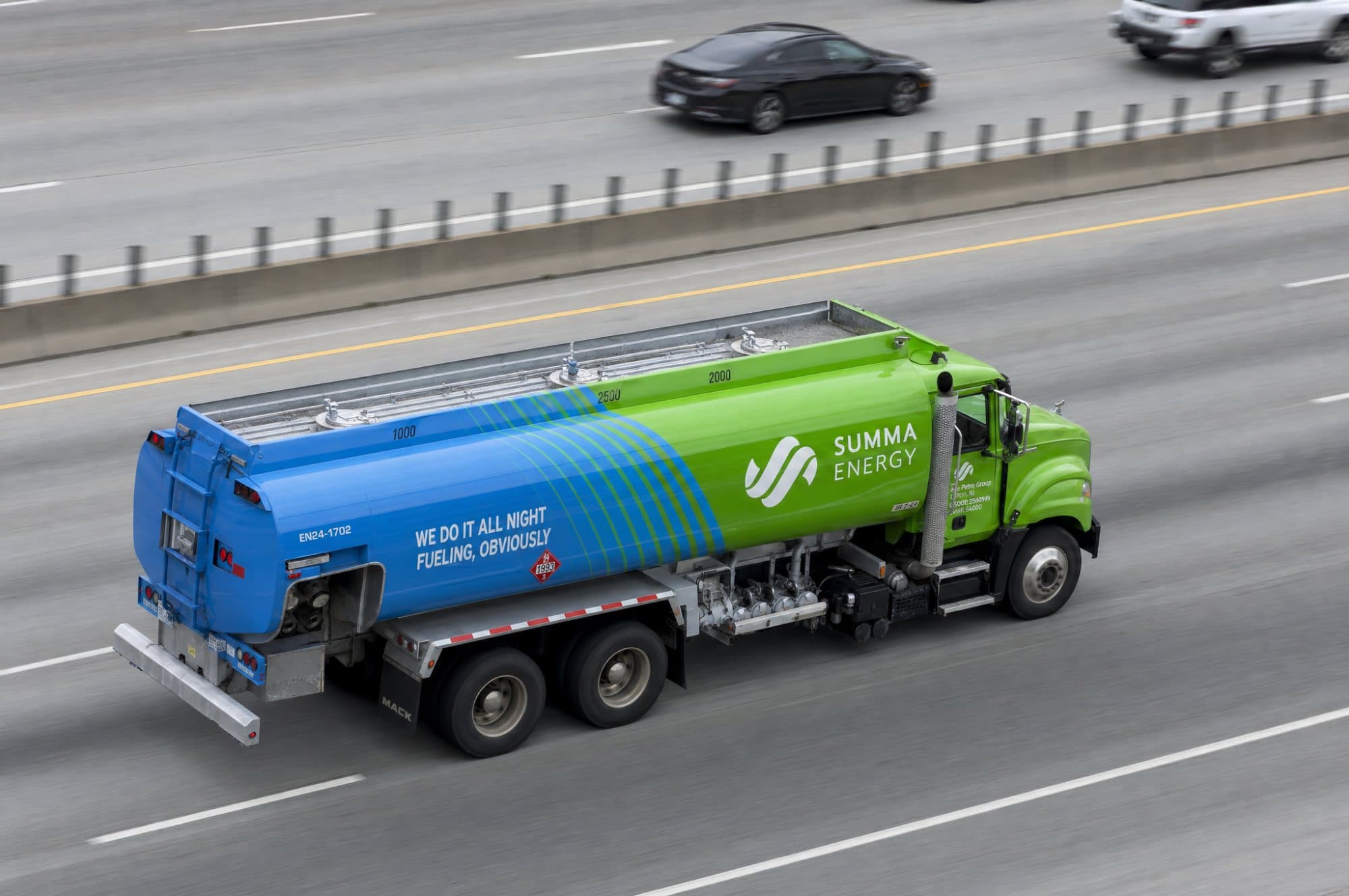A Summa tanker travelling a multi-lane highway, seen from an overpass above with the road blurred by its speed.